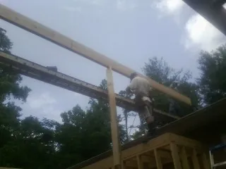 Carpenter setting a ridge beam over a new addition frame — Ice Dam Removal by Roofing Brothers in Osteen