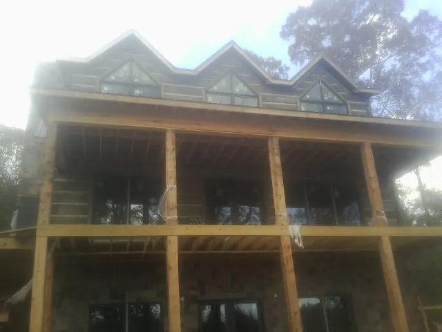 Dormers and porch framing on a large log home under construction — Roof Coating work by our crew in Osteen