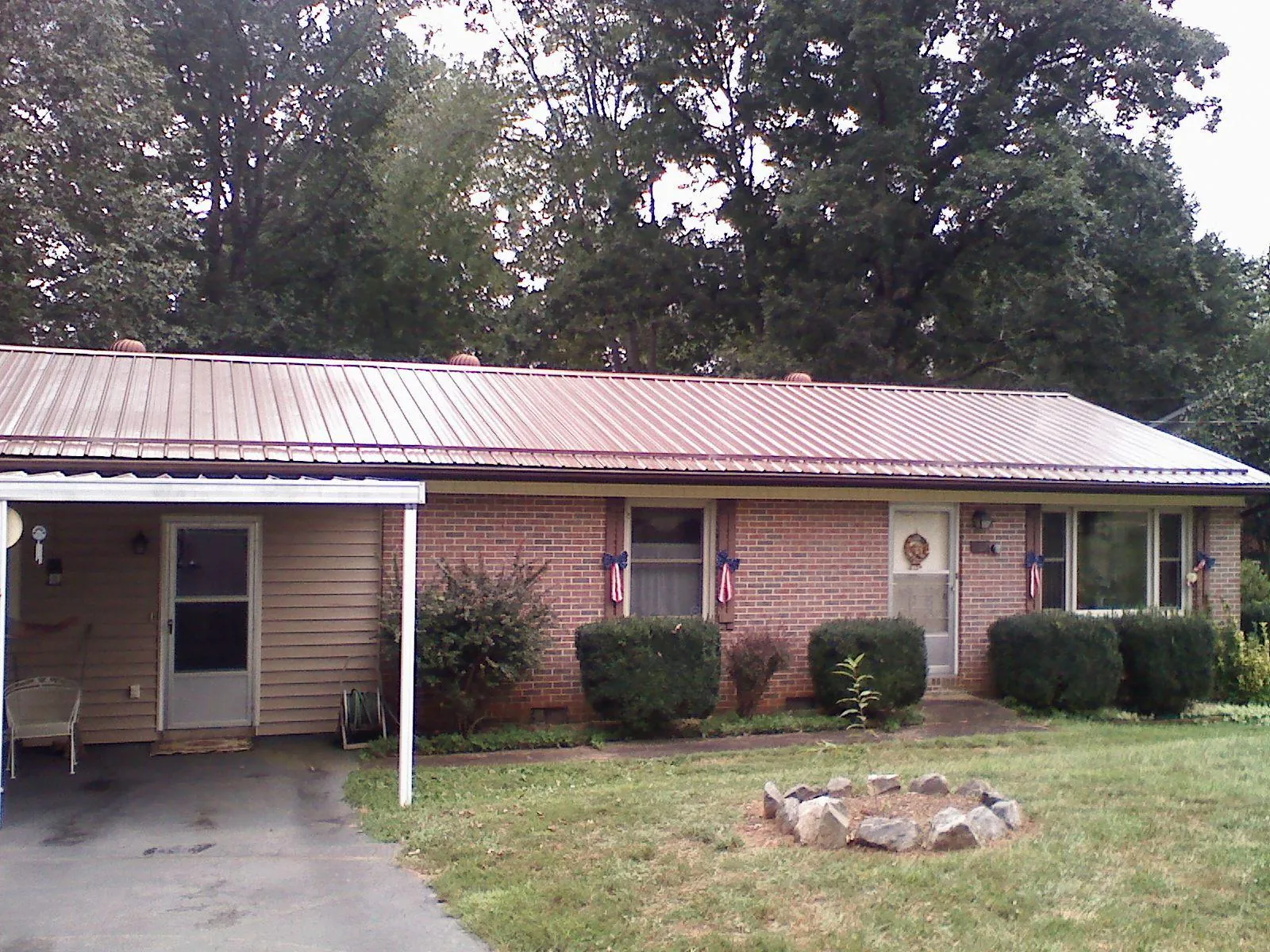 Bronze metal roof and carport on a brick ranch home — Roof Repair work by our crew in Osteen