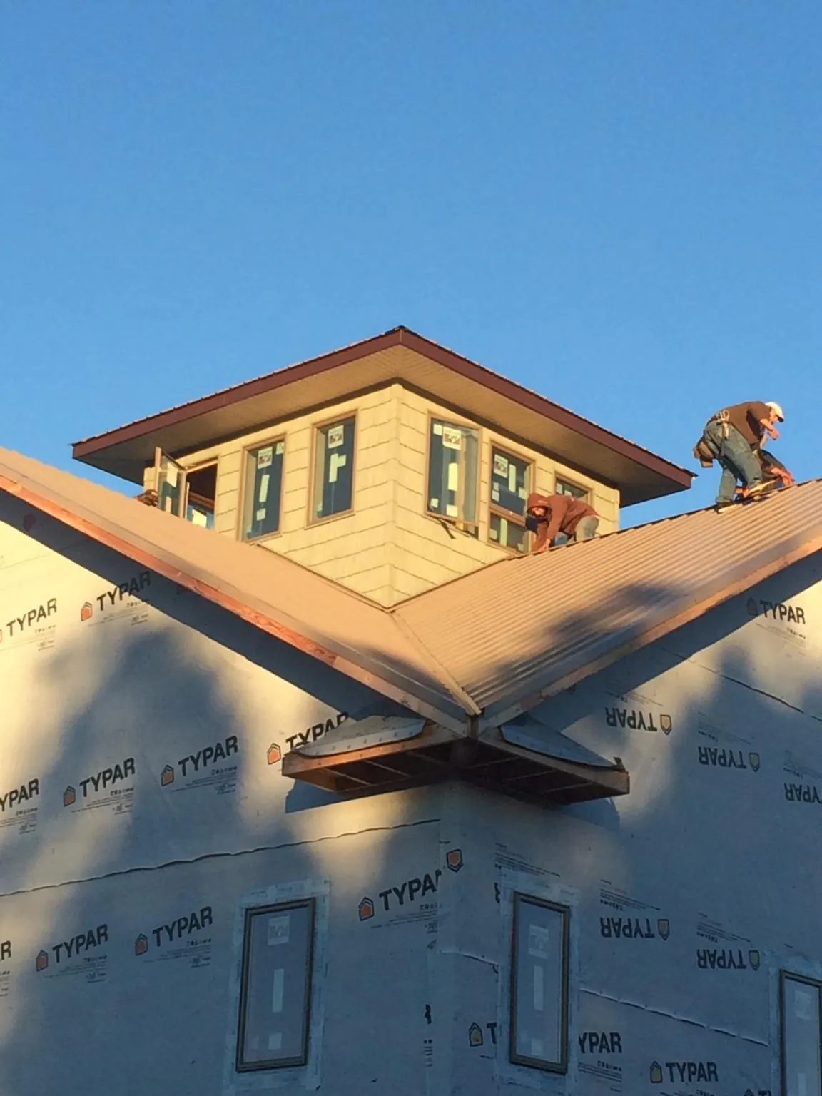Roofers working around a rooftop cupola on a new metal roof at sunset — Roof Waterproofing in Osteen by Roofing Brothers